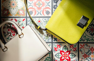 Joyas y accesorios. Cartera blanca y cartera verde neon sobre un patrón de mosaicos.