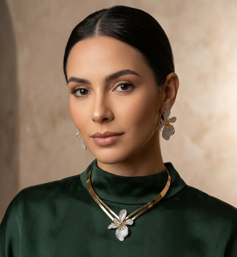 Joyas y Accesorios. Modelo luciendo joyas doradas con flores blancas.