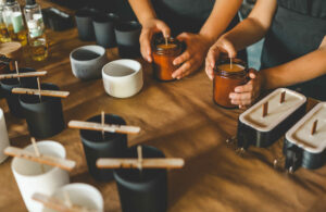 Personas haciendo velas sobre una mesa de madera.